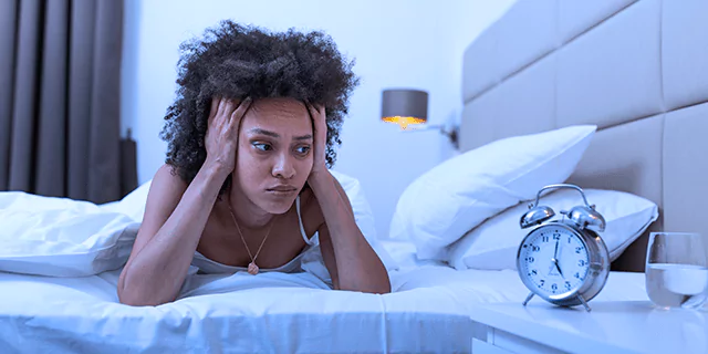 a person laying in bad and looking at a clock