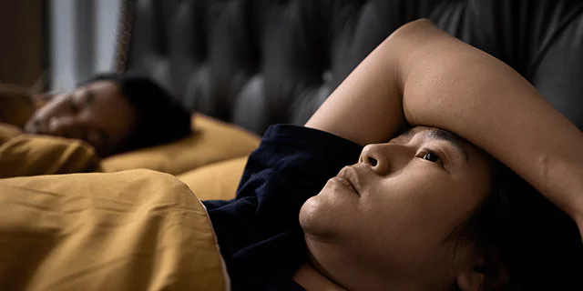 a person laying in beg and struggling with falling asleep