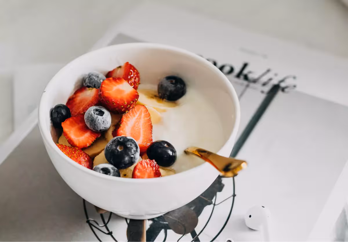 A white bowl filled with yogurt, strawberries and blueberries