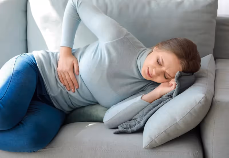 a girl laying down and clenching her stomach