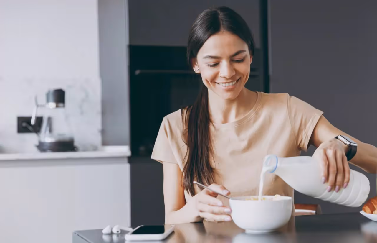 A woman pouring milk from a plastic bottle into a bowl