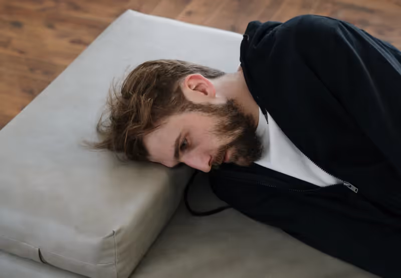 a man laying with his head on a pillow and looking frustrated