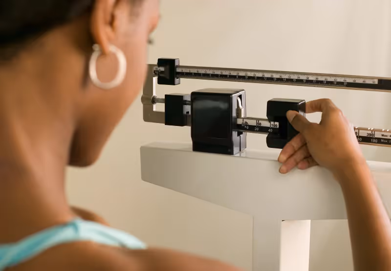 a woman weighing herself on a manual scale