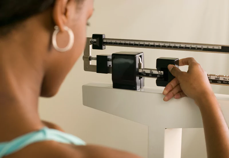 a woman weighing herself on a manual scale