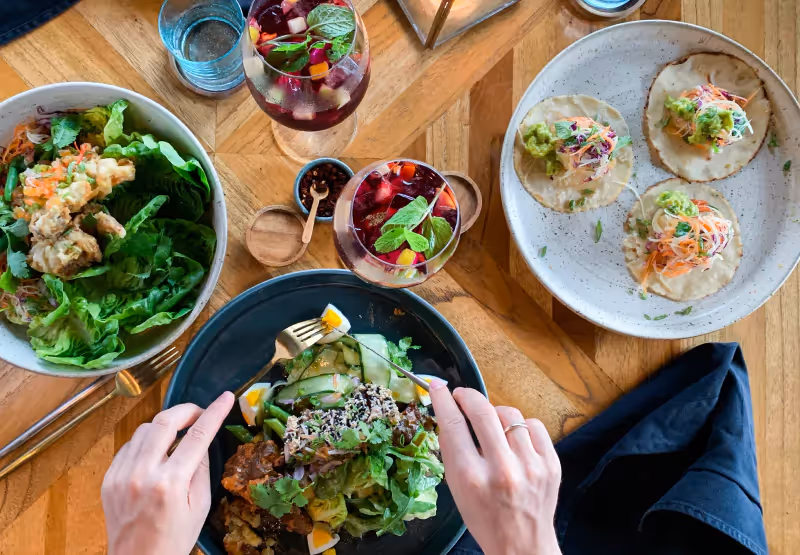 a spread of food and someone eating from a plate of salad