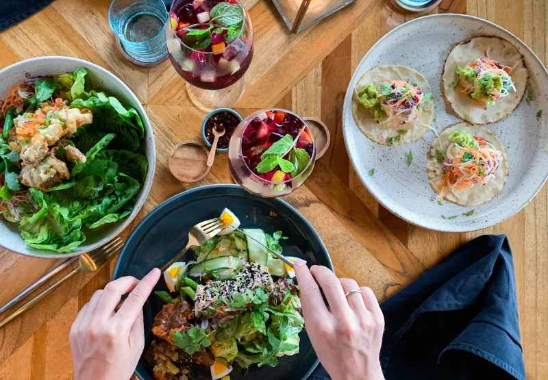 a spread of food and someone eating from a plate of salad