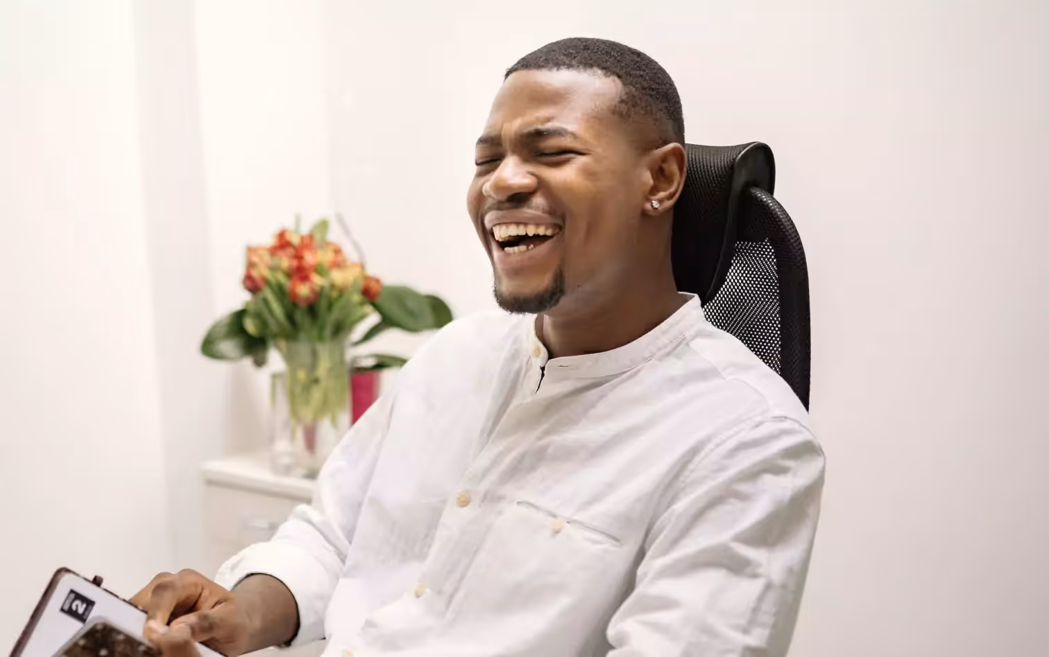 A man on an office chair, laughing