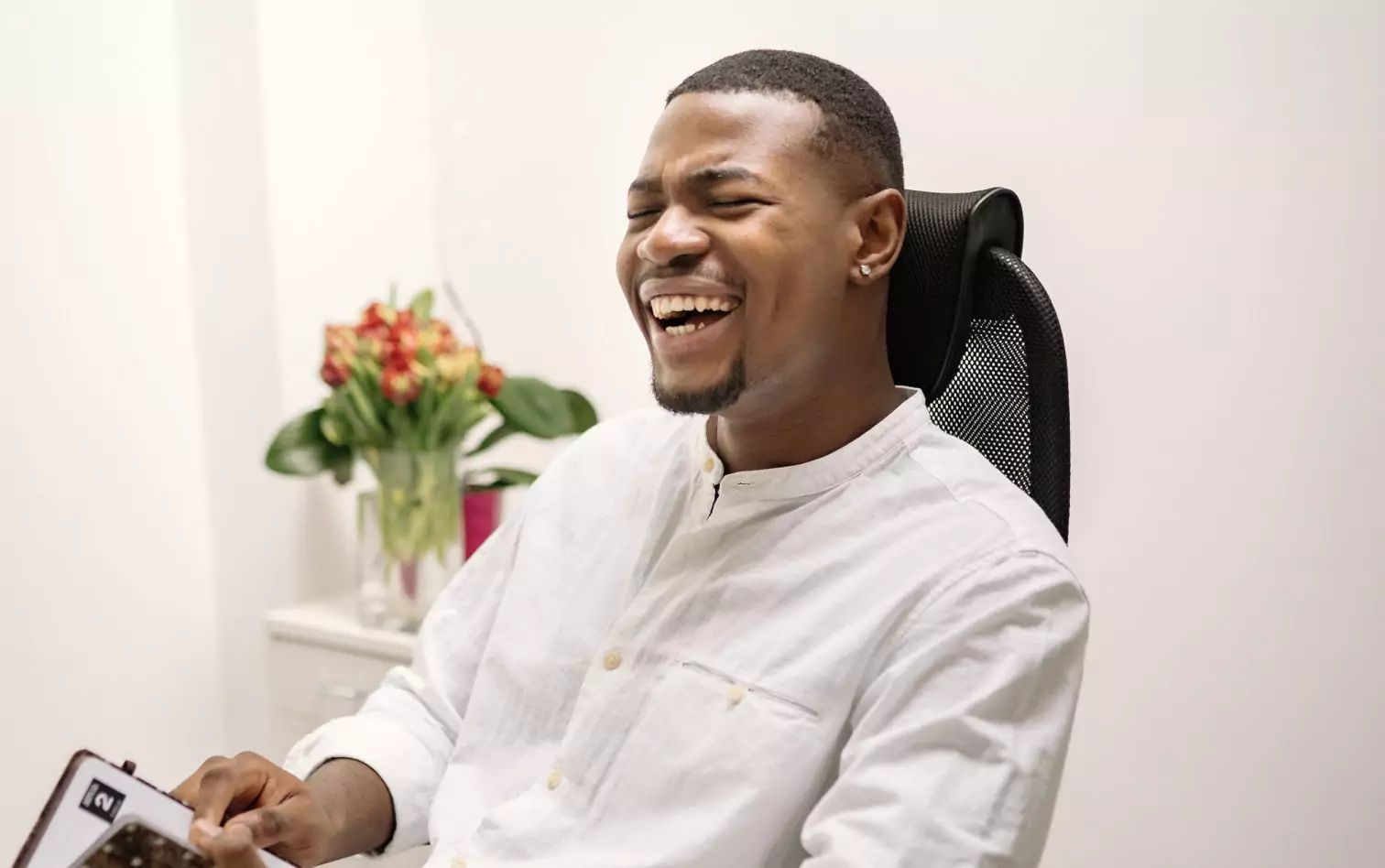 A man on an office chair, laughing