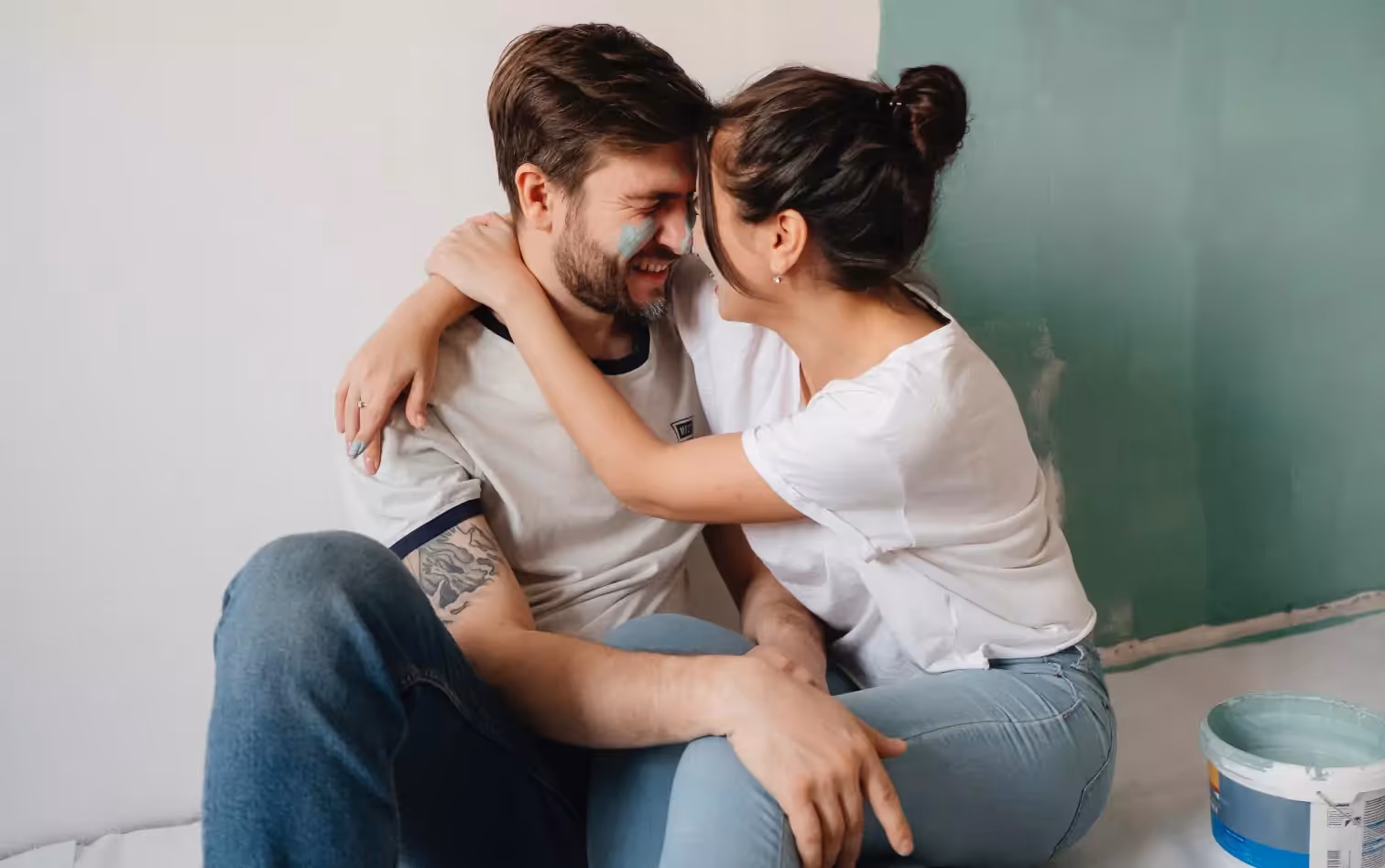 A couple taking a break from painting a room, holding each other and laughing