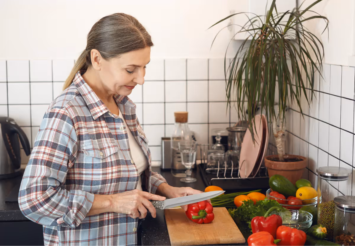 a woman chopping a red bell pepper