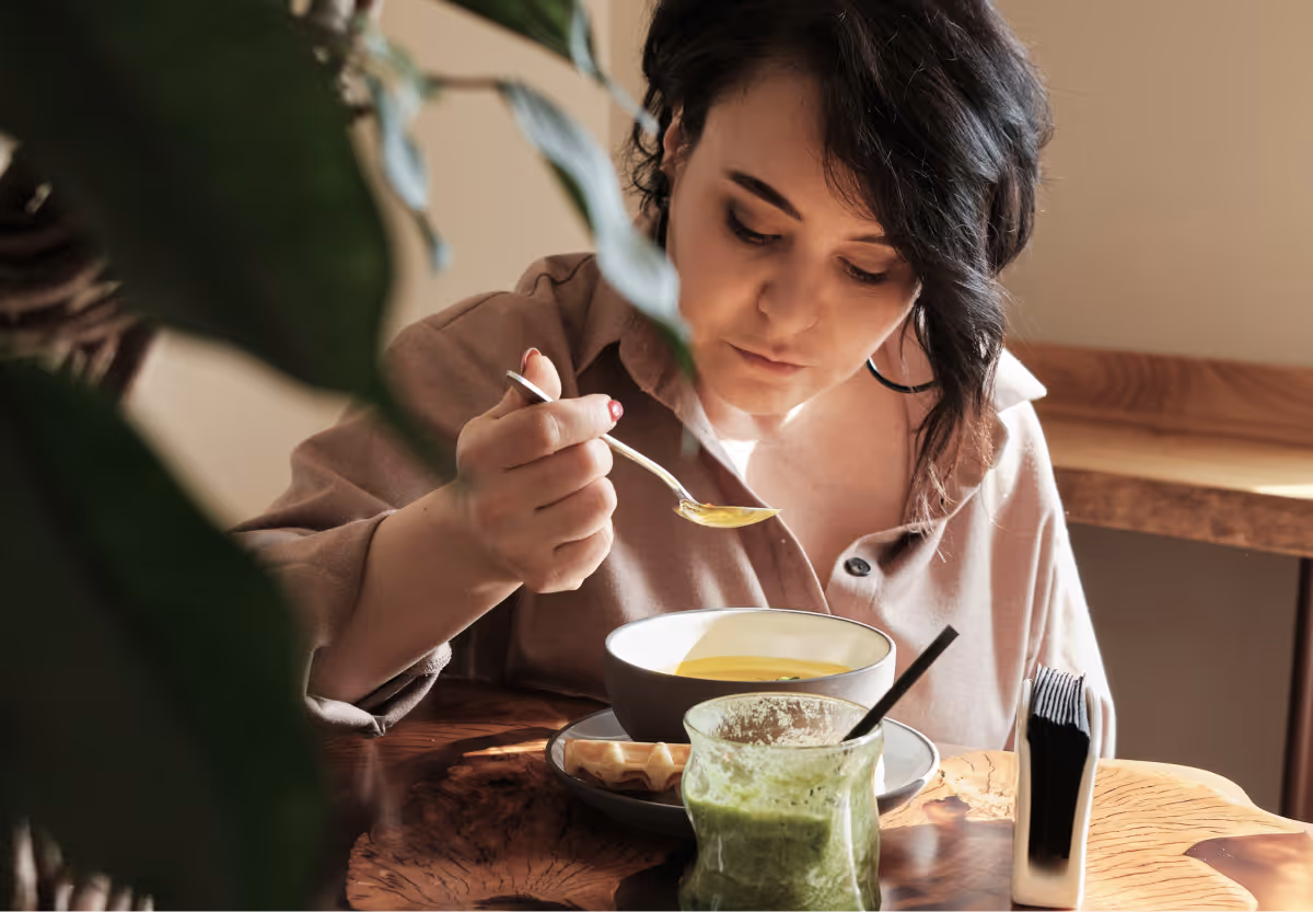A woman with brown hair eating soup
