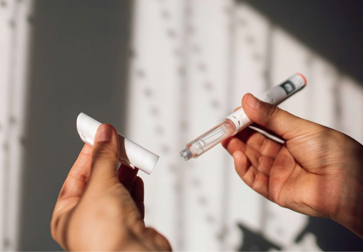 A pair of hands holding a GLP1 injection