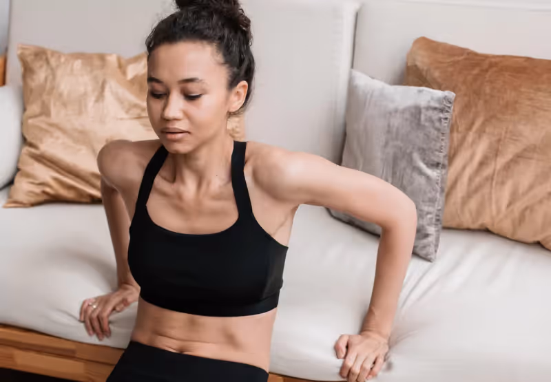 Woman doing exercises at home by the couch