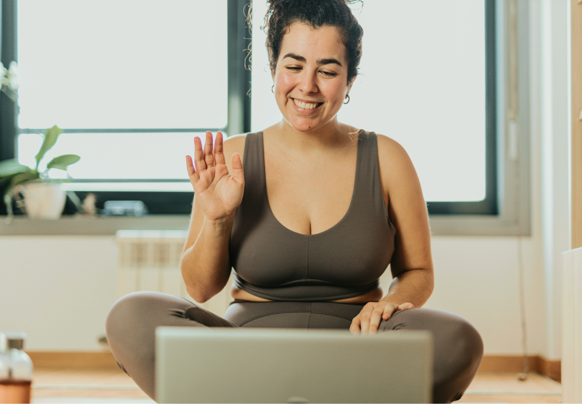 person in workout gear indoors chatting with an expert on a video call