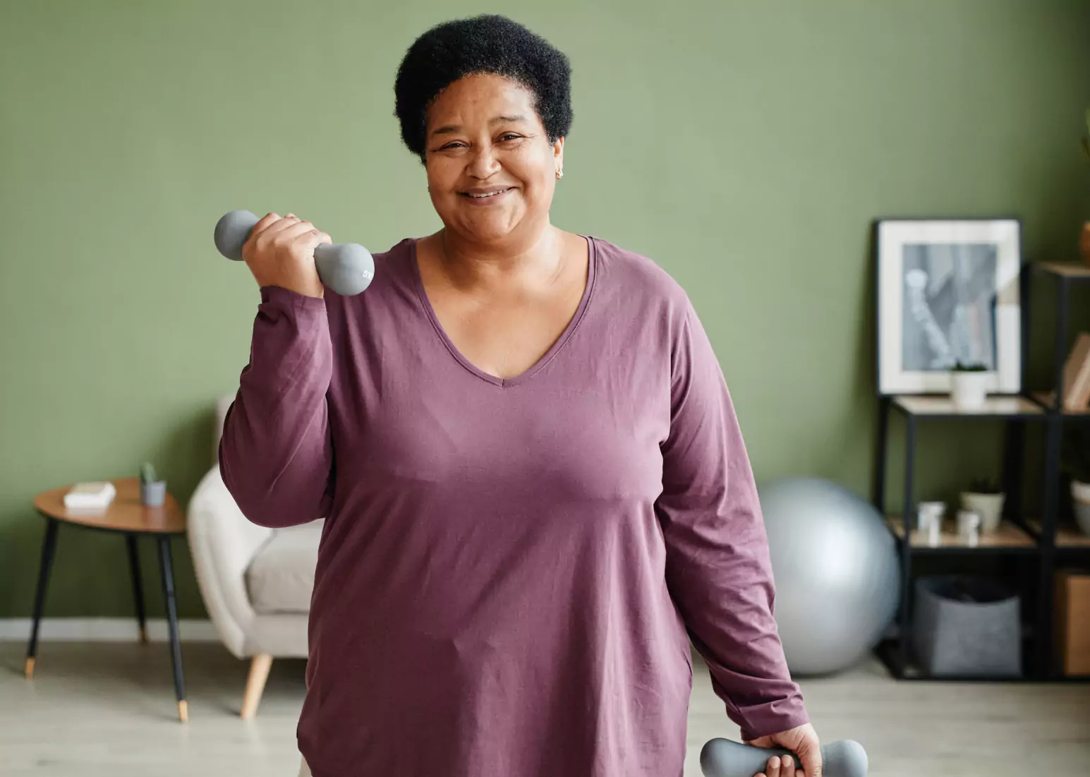 a woman with short black hair in a maroon top working out against green backdrop