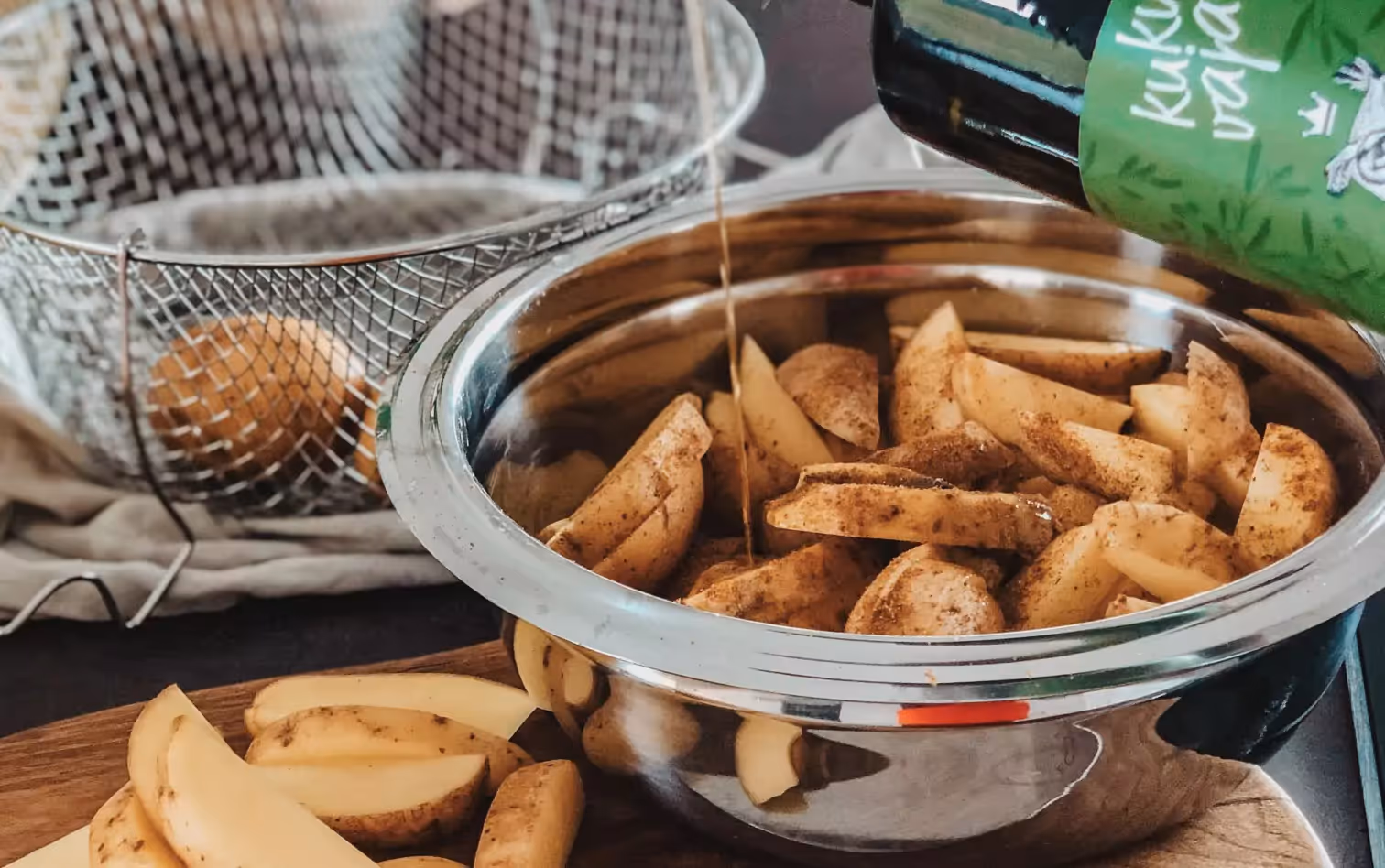 a person pouring oil in a bowl with potatoes 