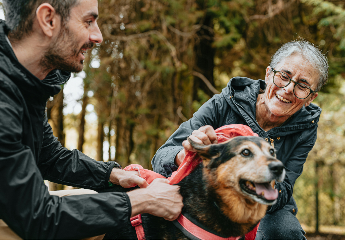 Two people outdoors, with a dog in a red leash