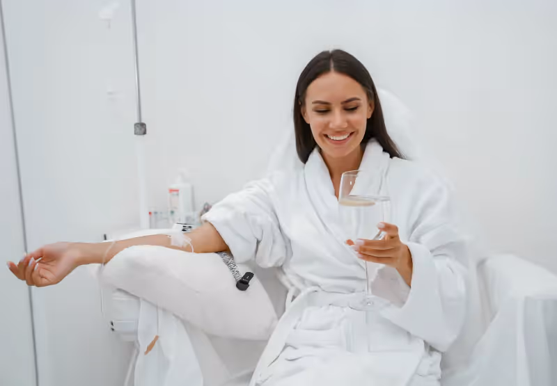 a woman getting an IV and drinking a glass of water