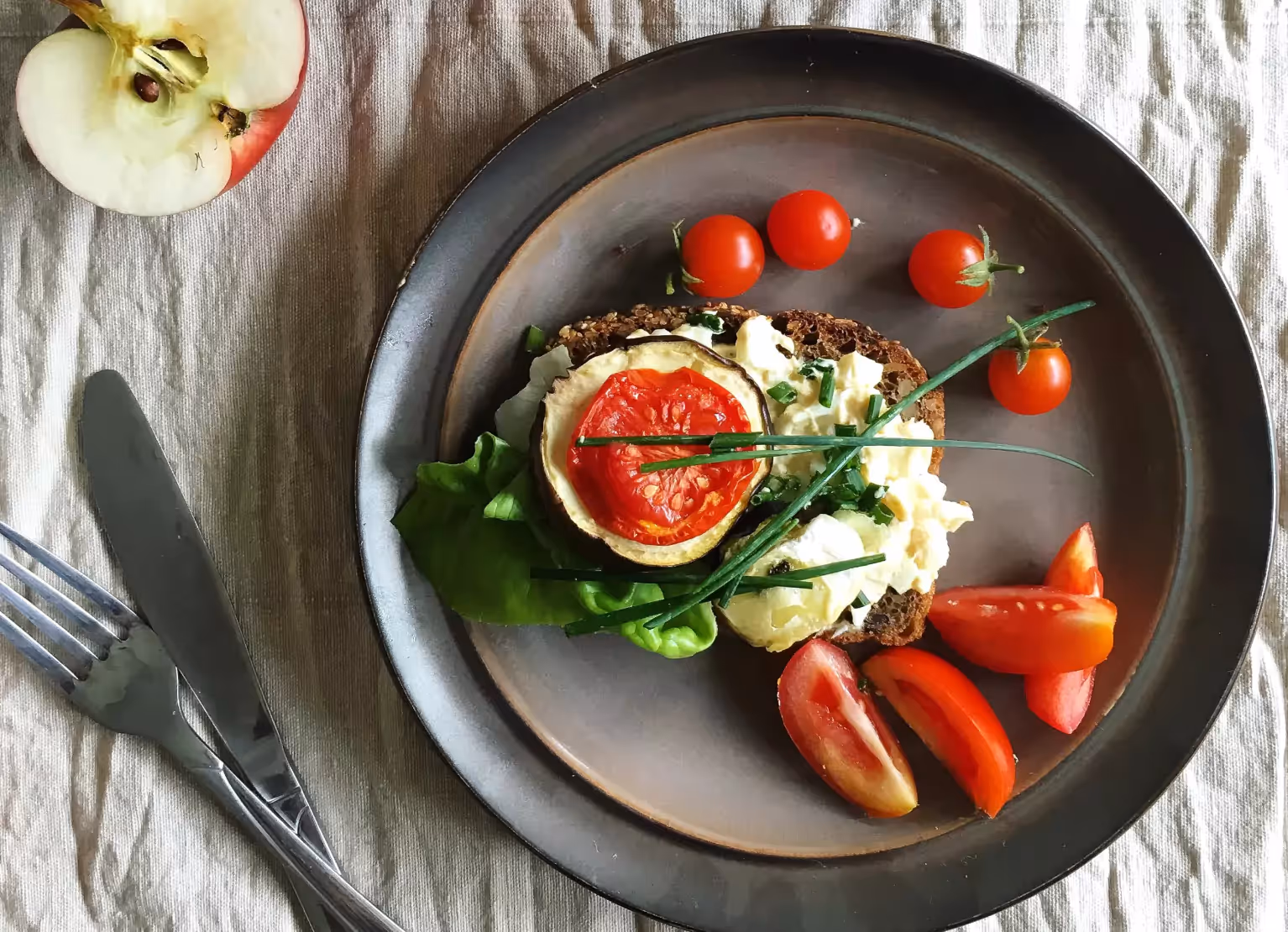a plate with a toast topped with potato salad and tomatoes