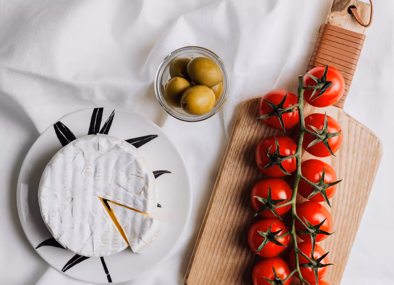 a board with tomatoes, olives and cheese