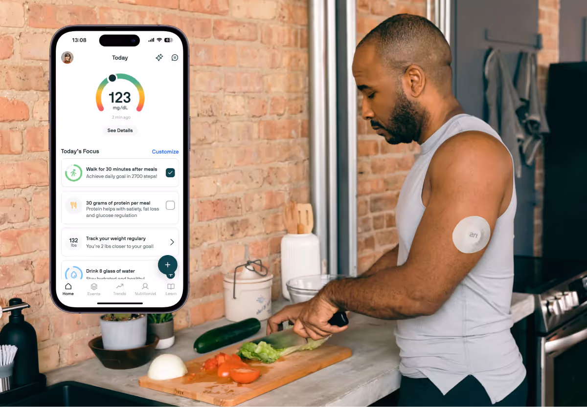 A man in the kitchen chopping vegetables wearing a CGM, with a shot of the Nutrisense app dashboard overlaid