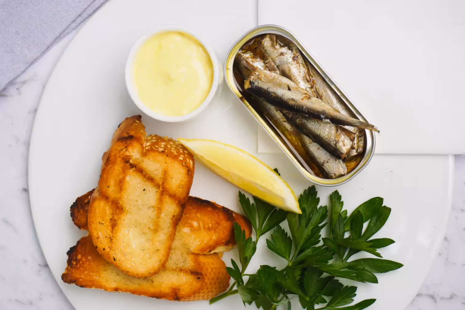 a can of sardines, toasts and a slice of lemon