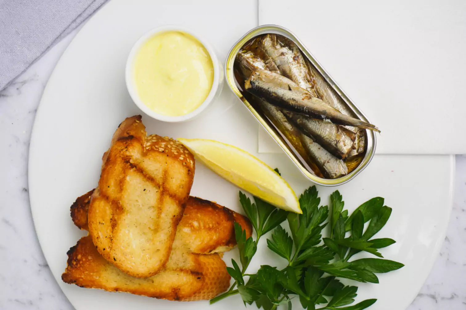 a can of sardines, toasts and a slice of lemon