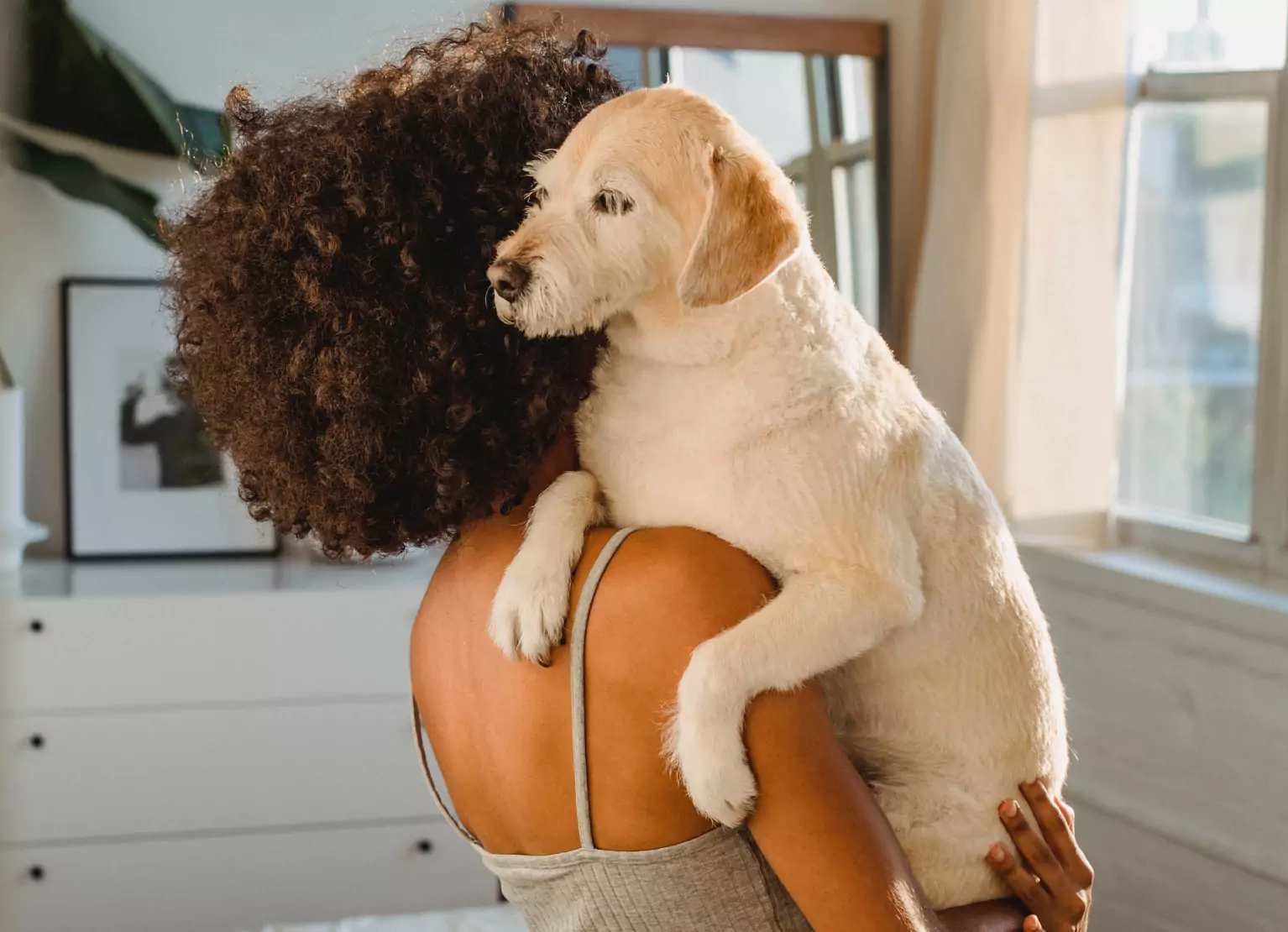 a girl holding a dog over her shoulder