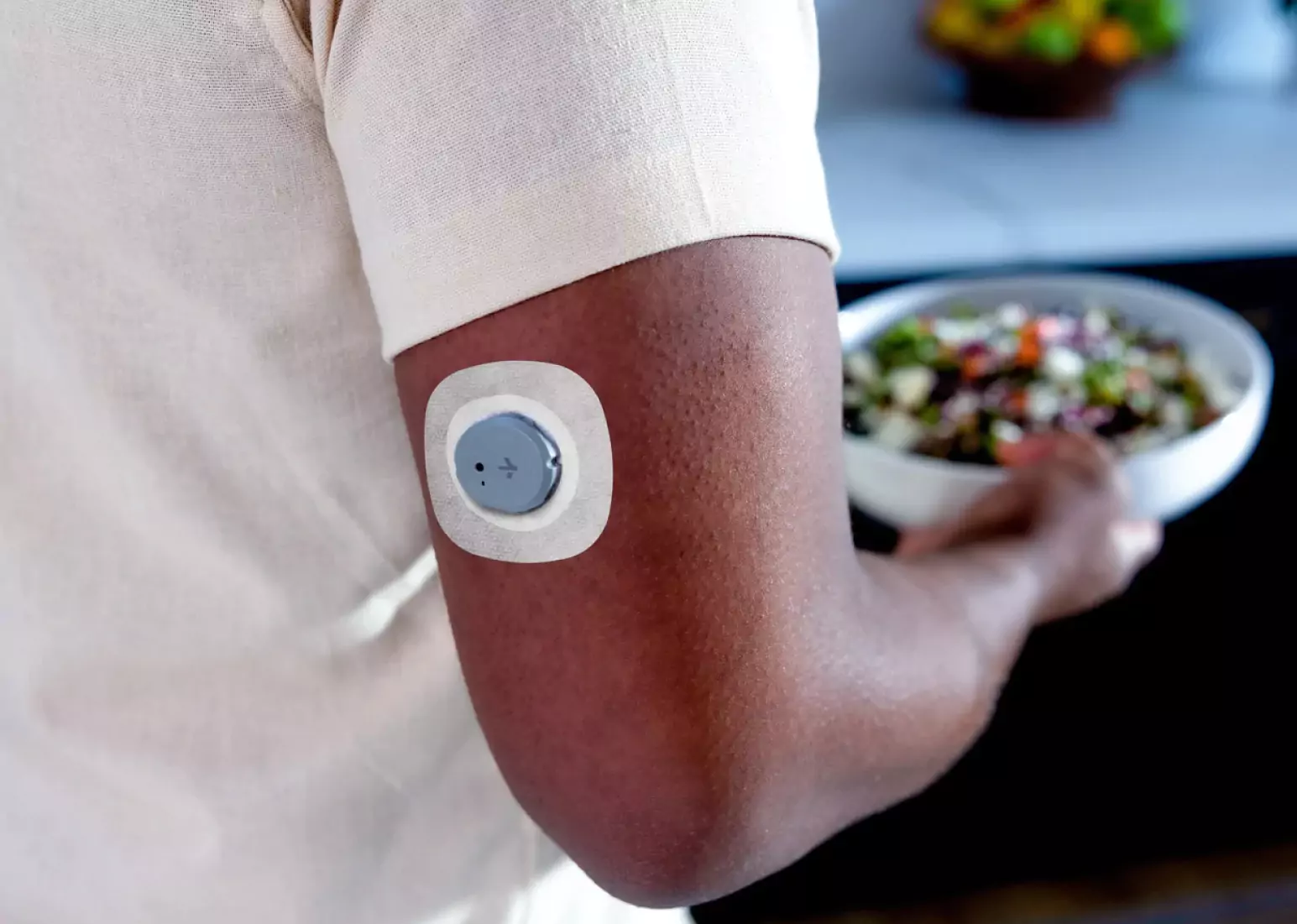 A closeup of the arm of a person wearing a cgm sensor, activating it with a mobile phone 