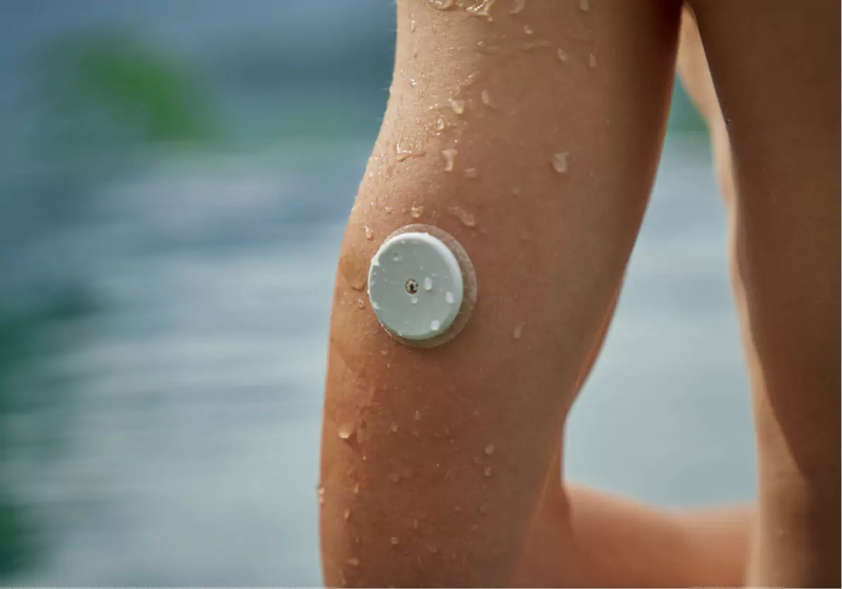 a person wearing a CGM outdoors near the water likely at the beach