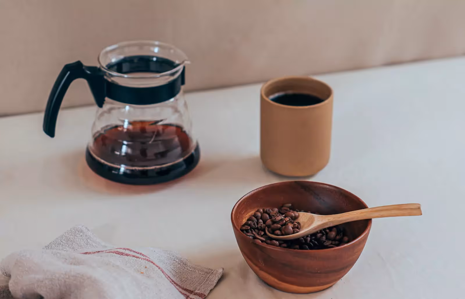 a pot of coffee, a cup of coffee and a bowl of coffee beans