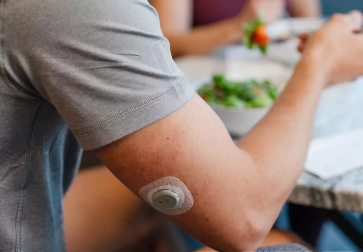 a person wearing a glucose biosensor on their arm while eating