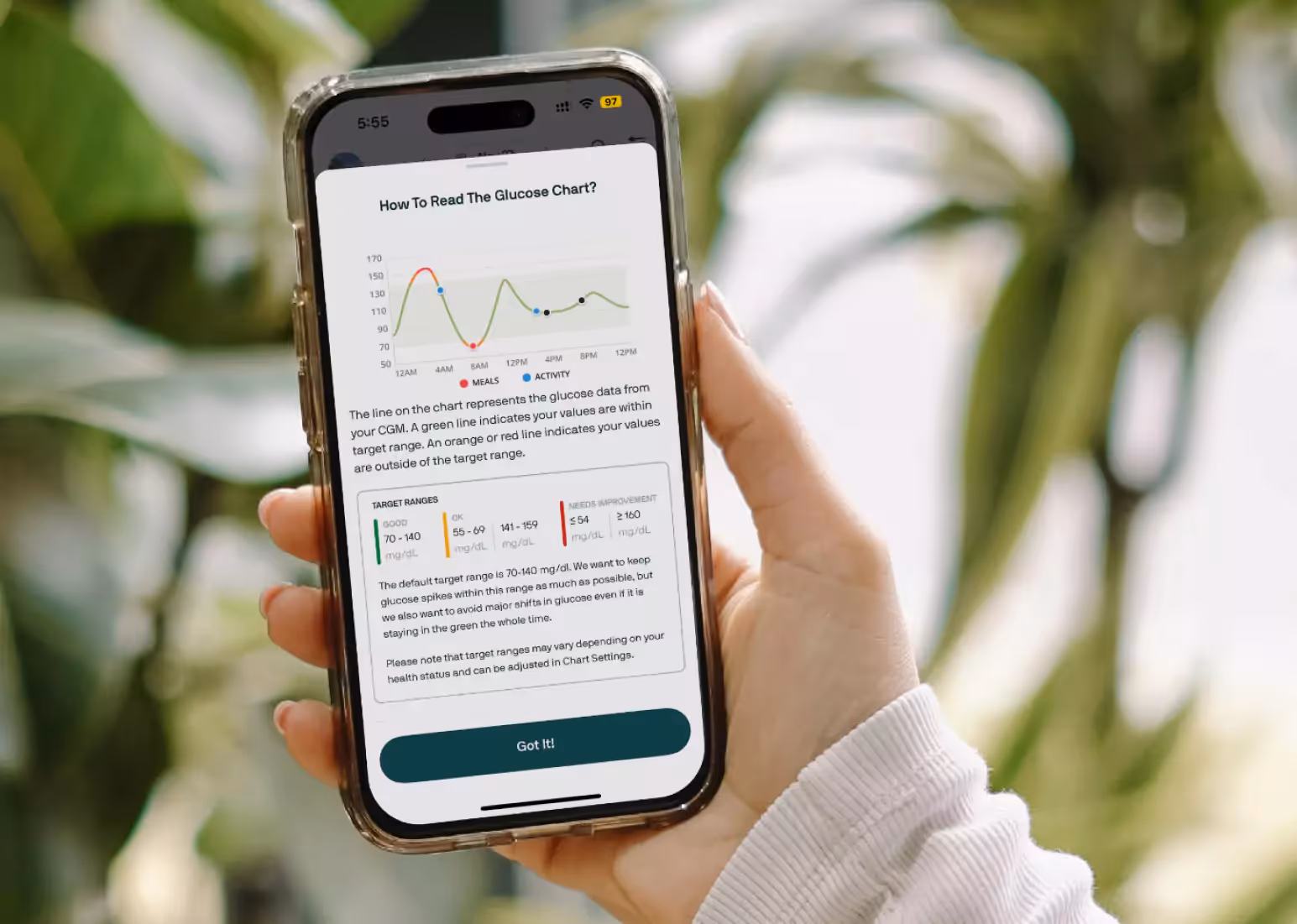 A hand holding a phone with the Nutrisense app open, reading a blood sugar log