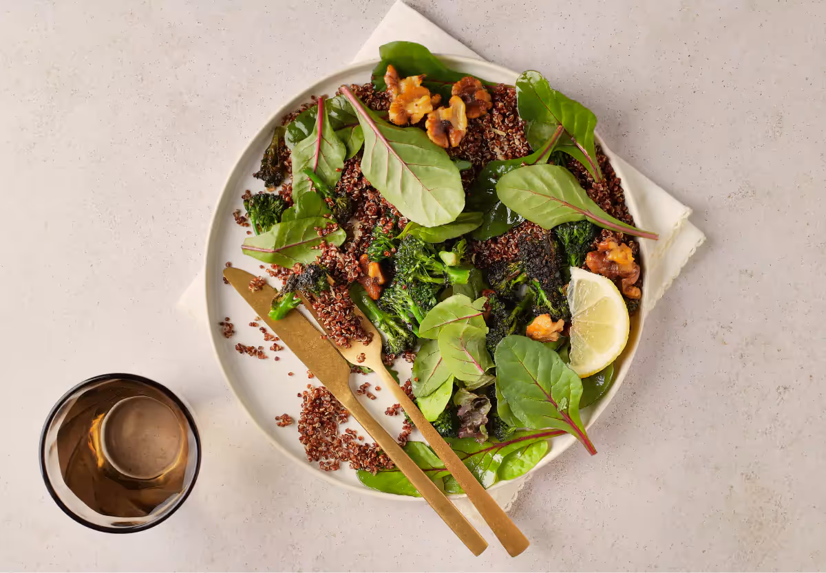 White bowl of a salad with fresh vegetables, grains and nuts on a beige background