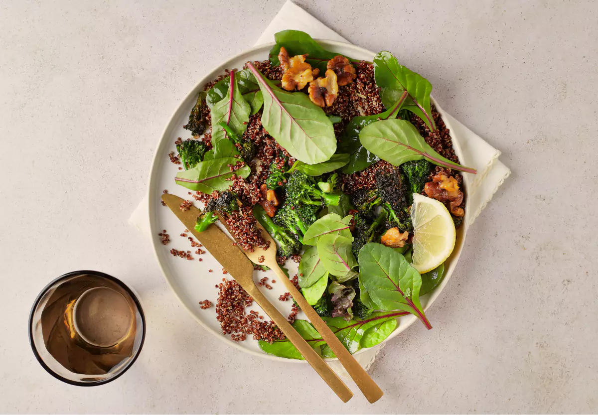 White bowl of a salad with fresh vegetables, grains and nuts on a beige background