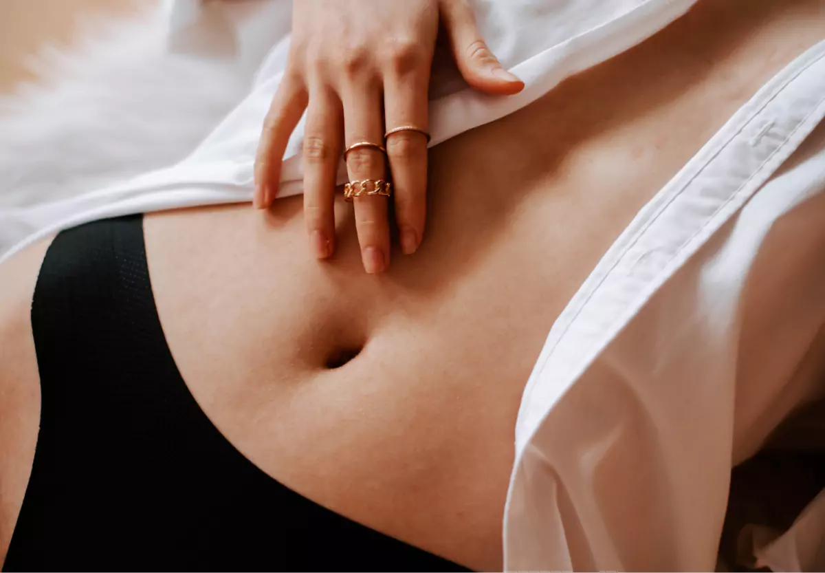 Closeup of a person's stomach, and a hand with gold rings on them