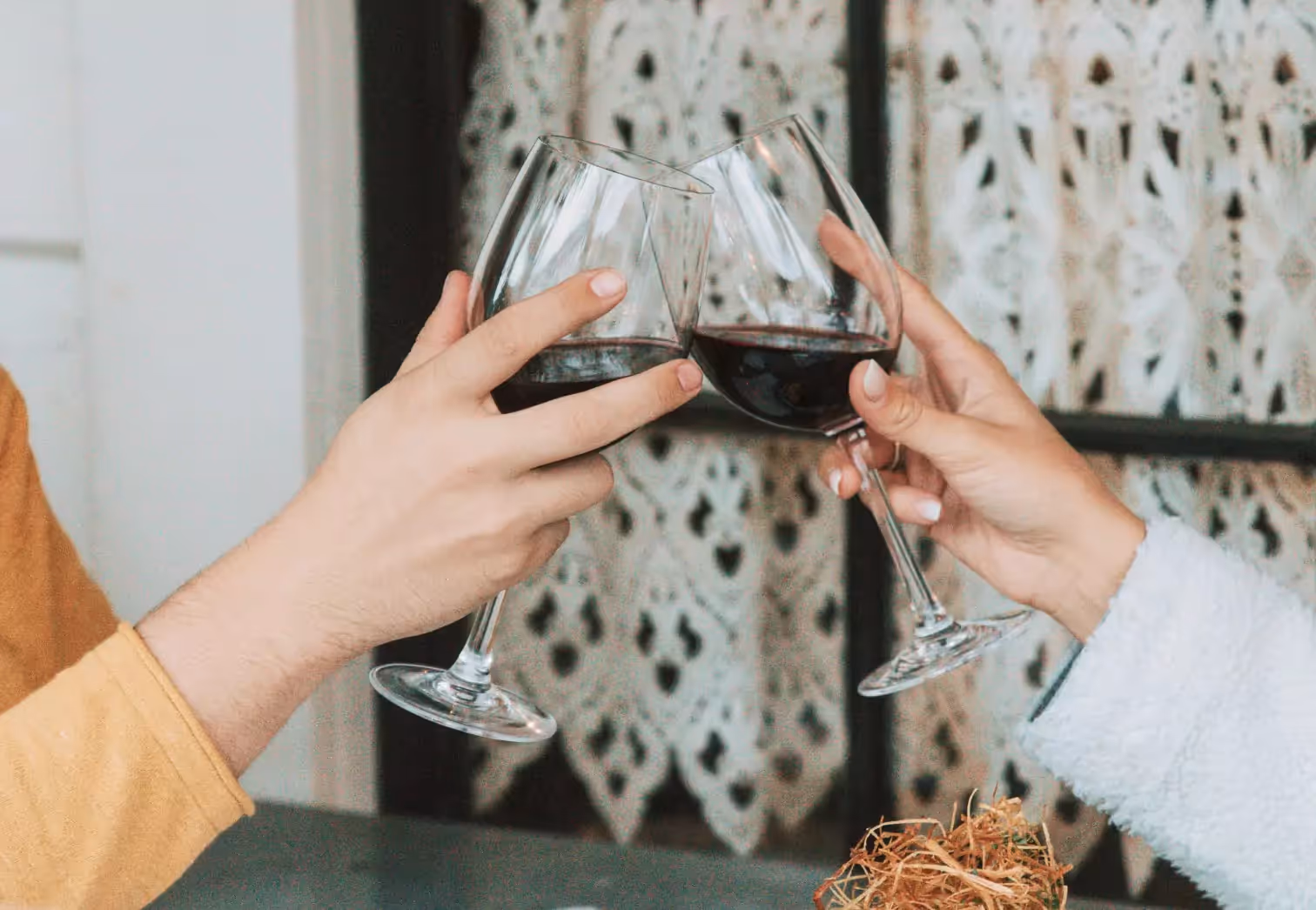 two people clinking glasses of red wine