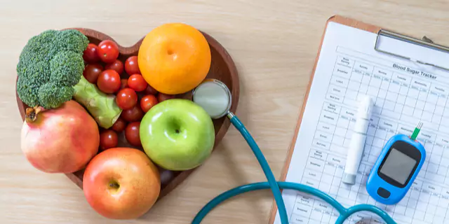 a heart-shaped plate of fits and veggies, a notebook, a glucose monitor and a stethoscope