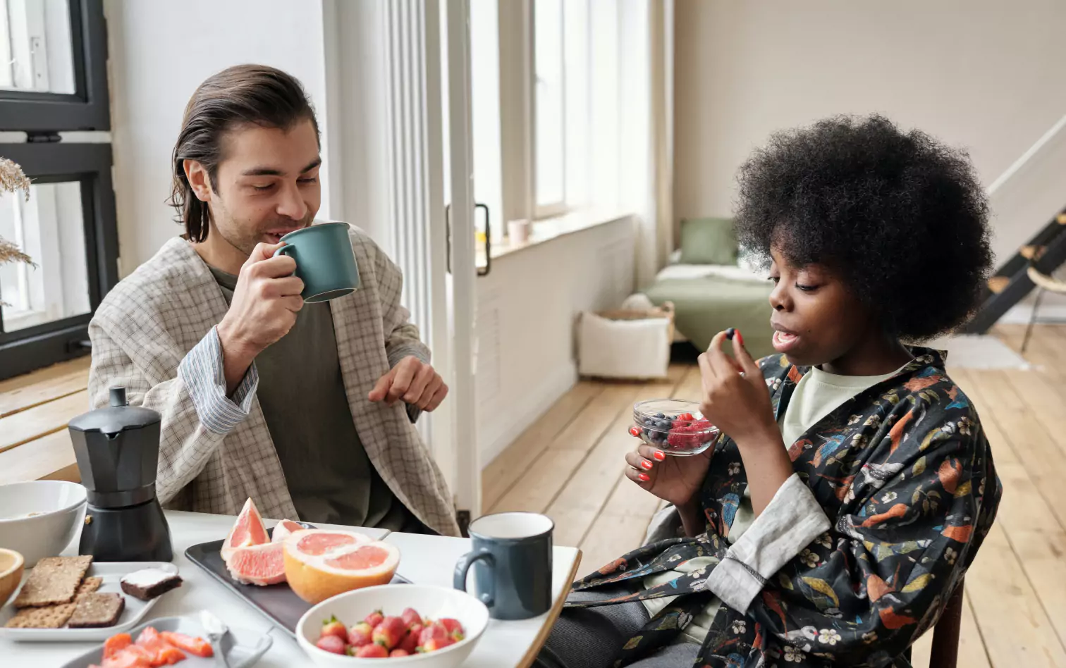 a couple of people eating berries and fruits for breakfast