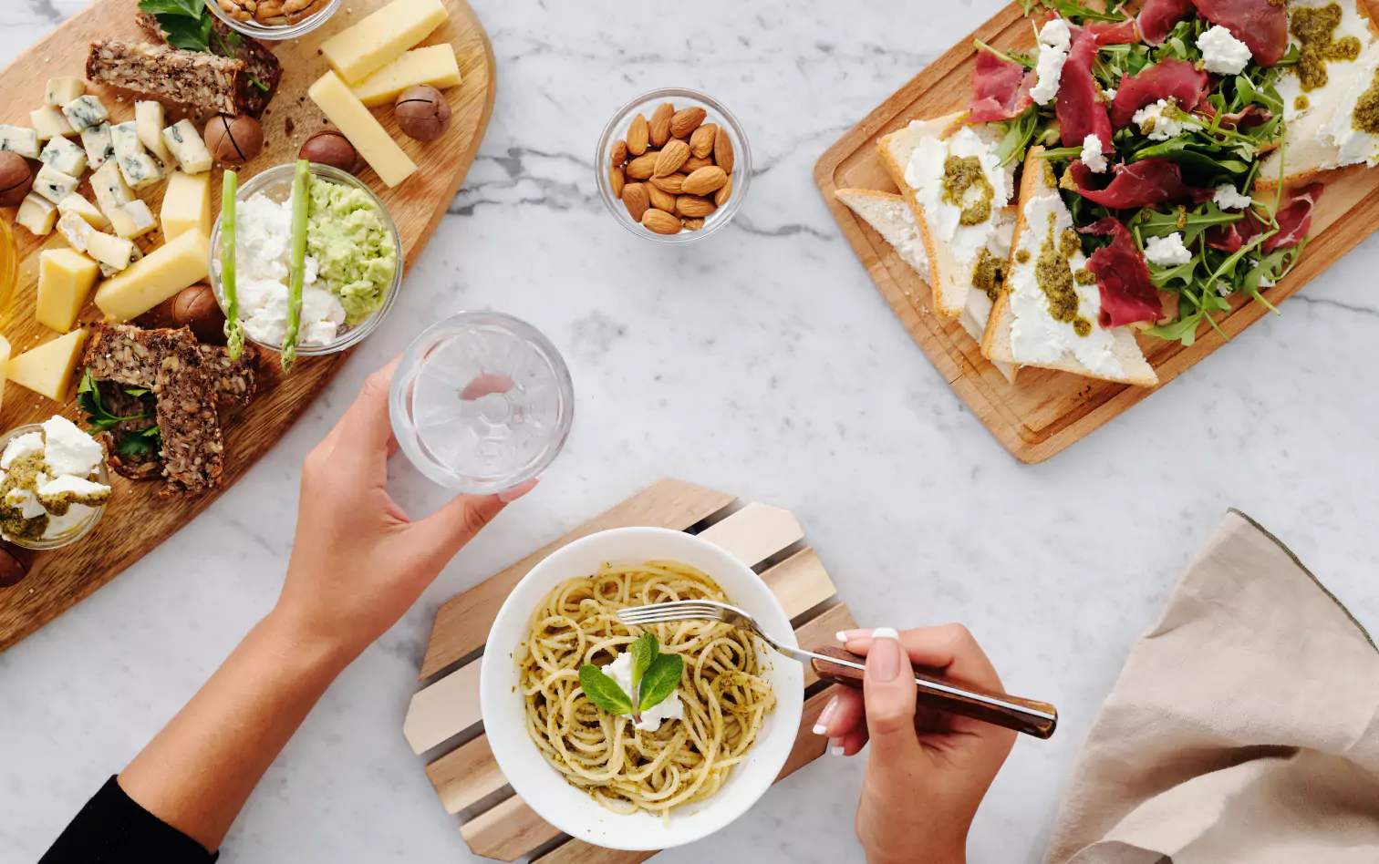 a person eating noodles, different types of cheese on cutting board