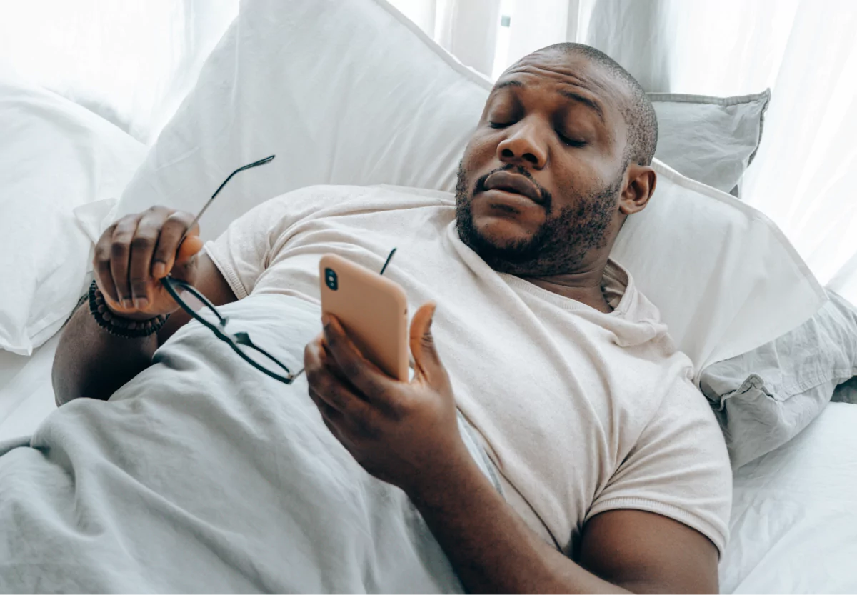 a man laying in bed and falling asleep with a phone in his hand