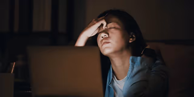 a person sitting in front of the laptop, looking tired