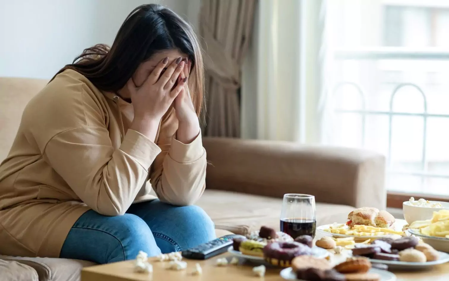 a person sitting at a table full of unhealthy food, looking stressed out