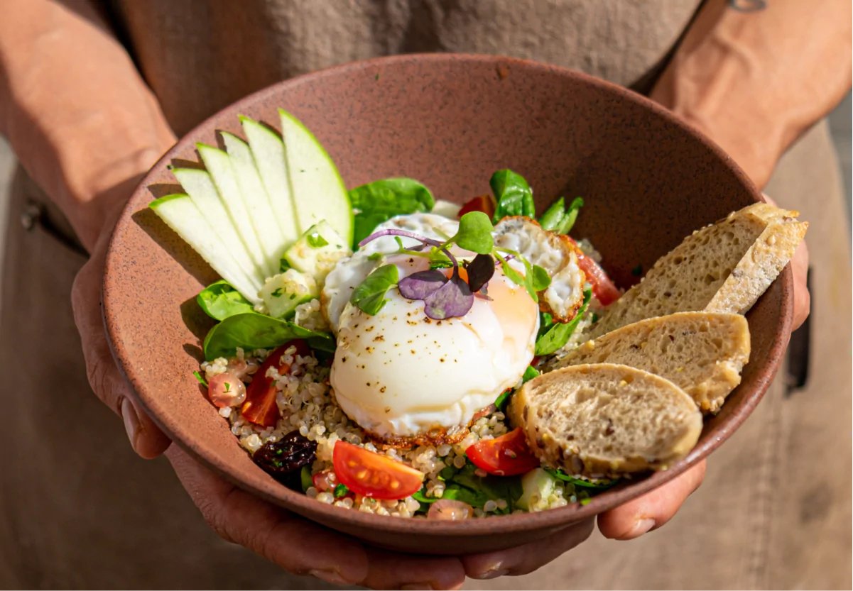 a bowl of quinoa with veggies, egg, and bread