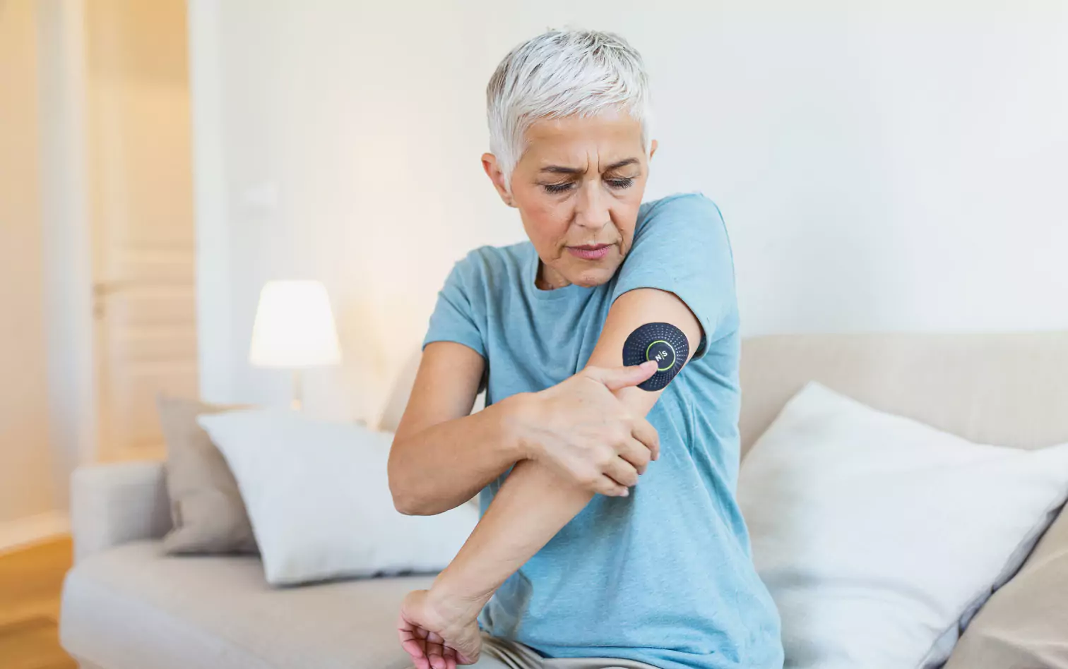 a person looking at their CGM sensor on their upper am