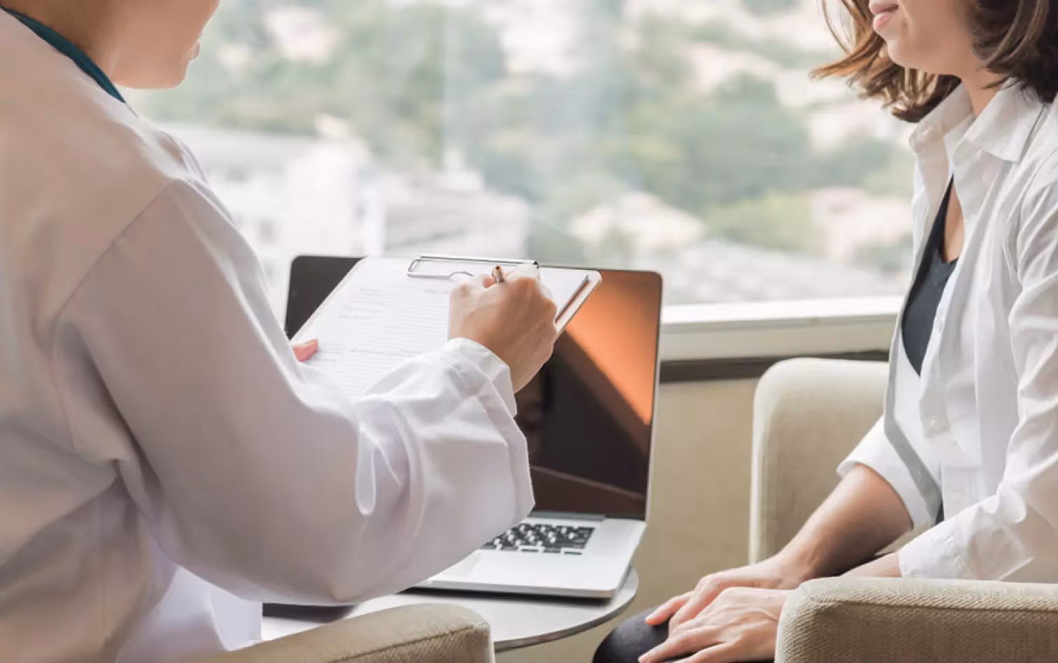 a doctor making notes and talking to a patient 