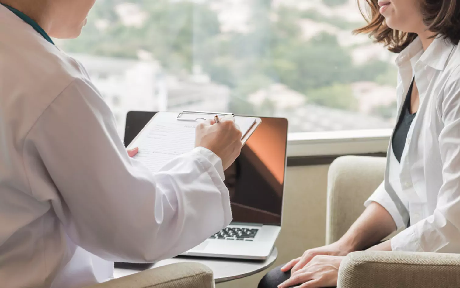 a doctor making notes and talking to a patient