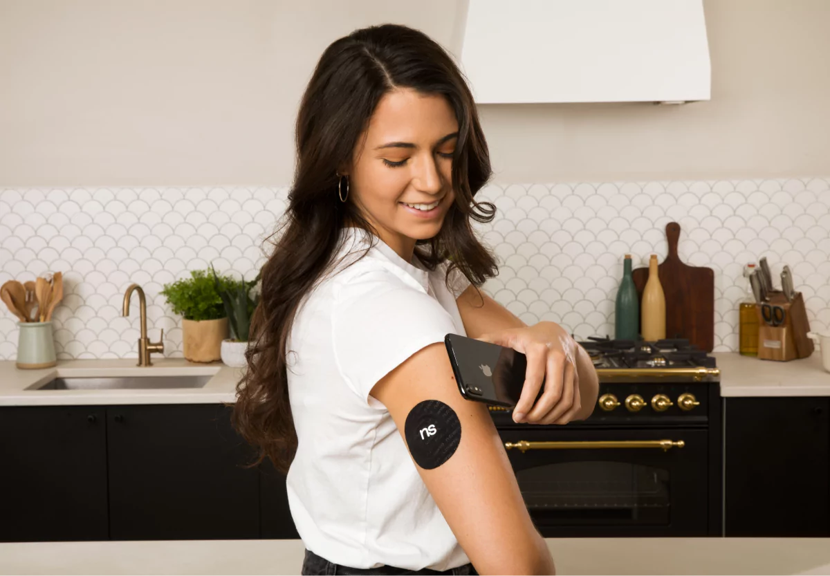 a woman scanning her continuous glucose monitor