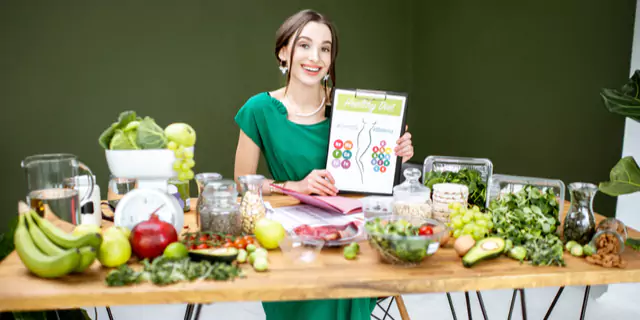 a dietitian sitting at a table full of veggies and fruits 