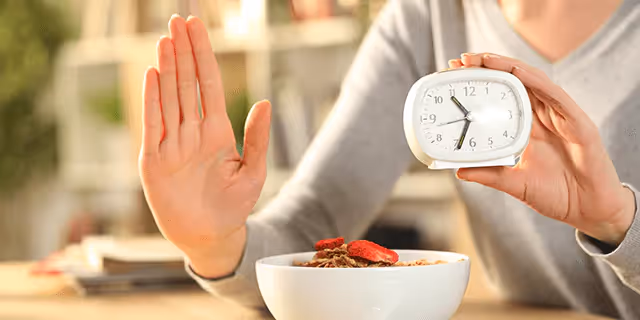 a person showing a stop sign with one hand and holding a clock with another hand